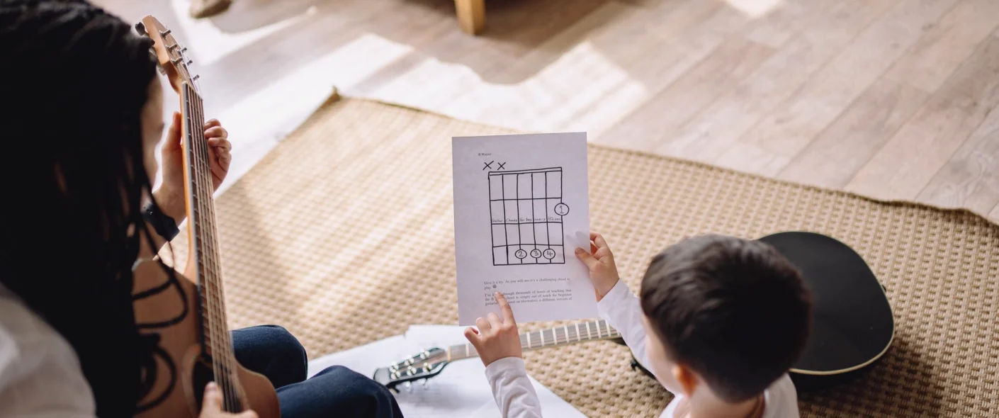 Gitarrenstunde im Unterrichtsraum: Haltung und Griffe werden gemeinsam erarbeitet